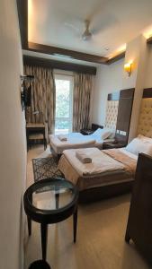 een hotelkamer met drie bedden en een tafel bij Metropolis Tourist Home Paharganj in New Delhi