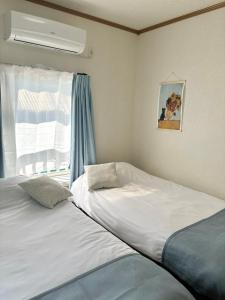 two beds in a room with a window at 四ツ木駅徒歩2分リノベーション済み家具家電無料WiFi完備スカイツリー電車5分 in Tokyo