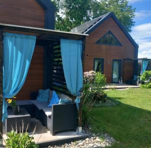 a patio with blue curtains in front of a house at Eleonor Accommodation in Liszki