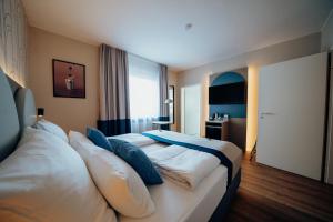 una camera d'albergo con un grande letto con cuscini di guestified LIYANA a Ratingen