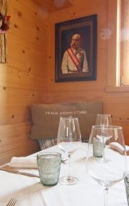 een tafel met wijnglazen en een foto van een man bij Ciasa Vervei in Cortina dʼAmpezzo