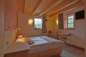 1 dormitorio con cama, escritorio y ventana en Ciasa Vervei, en Cortina dʼAmpezzo