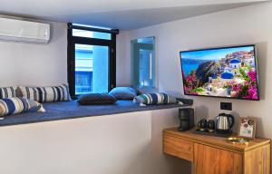 Habitación con TV en la pared con almohadas en CITYLUXE Suites & Rooms en Atenas