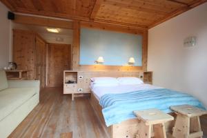 1 dormitorio con 1 cama grande y 2 bancos de madera en Ciasa Vervei, en Cortina dʼAmpezzo