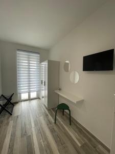 a white room with a bench and a television on a wall at Essentia Rooms & Relax in Vasto