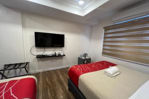 a room with two beds and a flat screen tv at Khotel Pasay in Manila