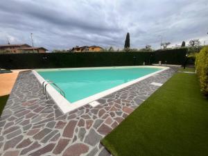 a swimming pool in a yard with a green lawn at Cherry House with Pool, Solarium Area and Barbecue in Manerba del Garda