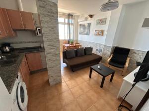 ein Wohnzimmer mit einem Sofa und einem Tisch in der Unterkunft Apartamento frente al Mar - Pedregalejo in Málaga