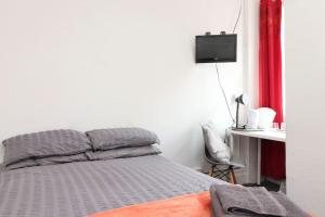 Un dormitorio con una cama y un escritorio con televisión. en Pebbles guest house, en Southampton