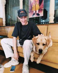 a young man sitting on a couch with a dog at The Elite Castle in Jaisalmer