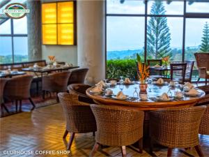 uma sala de jantar com mesa, cadeiras e janelas em Canyon Woods Resort Club Tagaytay em Tagaytay