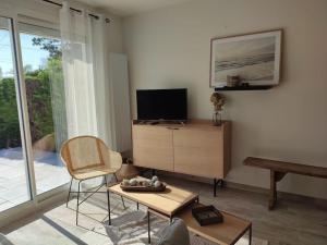 LanchèresにあるLes étoiles de la Baieのテレビと椅子とテーブルのあるリビングルーム
