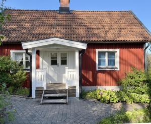 czerwony dom z białymi drzwiami i werandą w obiekcie Red cottage with a nice view of the landscape, at Aboda Klint w mieście Alsterbro