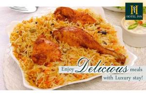 un piatto di cibo con pollo e riso su un tavolo di Hotel Inn a Karachi