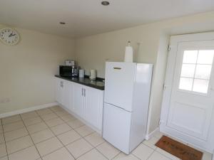 a kitchen with a white refrigerator and a clock at Pentre Iago in Holyhead +15 photos