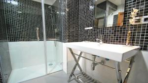 La salle de bains est pourvue d'un lavabo et d'une douche. dans l'établissement Apartamentos Living Sevilla Centro Maestranza, à Séville