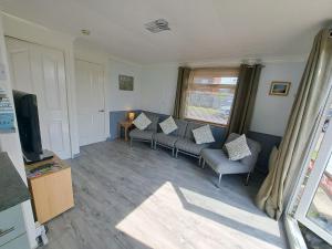 a living room with couches and a television at Beside the Sea Chalet, Mablethorpe in Mablethorpe