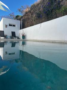 a pool of water next to a white wall at Villa Santorini in Torre de Benagalbón
