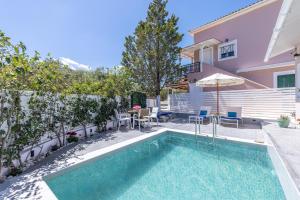a swimming pool with chairs and an umbrella next to a house at Soso's Garden Villa with Private Pool in Planos