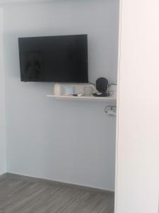 telewizor z płaskim ekranem siedzący na białej ścianie w obiekcie casaeudokia w mieście Apóllona