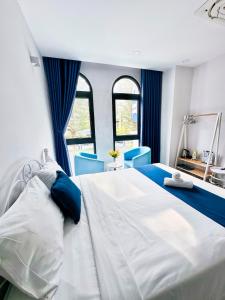 um quarto com uma grande cama branca e cadeiras azuis em Beach Hotel Grand World (La La Homestay) em Phu Quoc