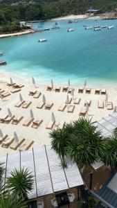 una vista sul tetto di una spiaggia con sedie e ombrelloni di HOTEL DENOEL a Ksamil