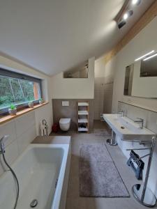ein Badezimmer mit einer Badewanne, 2 Waschbecken und einem WC in der Unterkunft Waldhaus Tiedtke in Wedemark