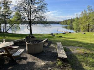 una mesa de picnic y un banco junto a un lago en Red cottage with a nice view of the landscape, at Aboda Klint en Alsterbro