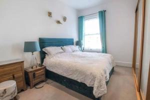 a bedroom with a bed with a blue headboard and a window at Middleton country retreat with airport parking . in Middleton One Row