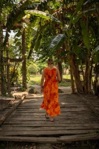 Eine Frau in einem orangenen Kleid, die auf einer Holzbrücke wandelt. in der Unterkunft Bardia Riverside View Park Resort in Bhurkīā