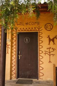 Eine schwarze Tür mit den Worten und kommt an die Wand in der Unterkunft Bardia Riverside View Park Resort in Bhurkīā
