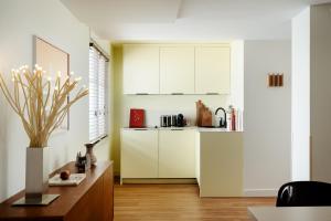 kuchnia z białymi szafkami i stołem w pokoju w obiekcie Edgar Suites Marais - Temple w Paryżu