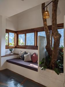 um banco num quarto com janelas e uma árvore em Kengbari Retreat em Gangtok