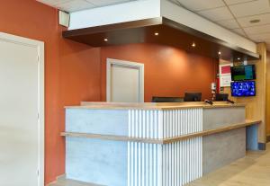 an office lobby with orange walls and a reception counter at B&B HOTEL Paris Porte de la Villette in Paris