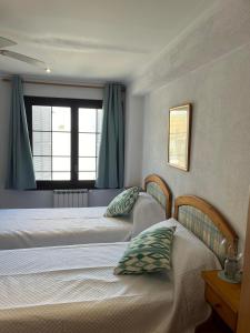 2 camas individuales en un dormitorio con ventana en HOSTAL RESTAURANTE CALA, en Cala Figuera