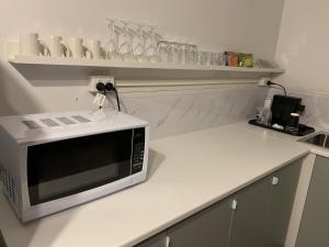 een witte keuken met een magnetron op een aanrecht bij The Reserve Hotel in Sale