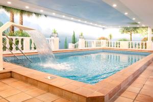 a swimming pool with a fountain in a building at Golf- und Wellnesshotel Amtsheide in Bad Bevensen