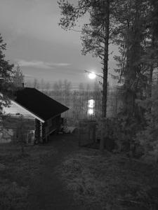 a small building in a field with a light at Cottage by the Muonio river for 6 person in Kolari
