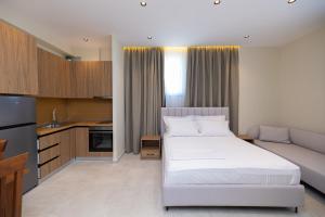 a bedroom with a white bed and a kitchen at Hotel Aluor in Vlorë