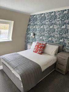 - une chambre avec un grand lit et du papier peint floral dans l'établissement Loch Ness Drumnadrochit Hotel, à Drumnadrochit