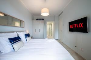 um quarto com uma cama branca e uma televisão na parede em Le COQ Charlene - Monaco à 50m - New em Beausoleil