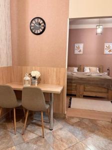 Habitación con mesa y cama con reloj en Alice Vendégház en Kalocsa