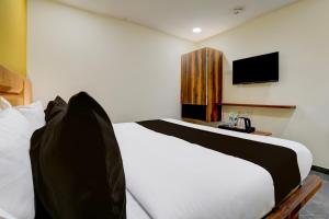 um quarto com uma cama branca e uma televisão em OYO Hotel Sunset em Ahmedabad