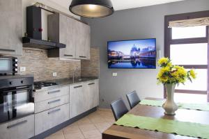 a kitchen with a table and a tv on the wall at Appartamento in Stile Minimale in Pontedera
