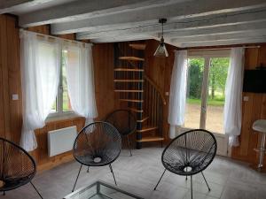 um quarto com 3 cadeiras e uma escada em espiral em Gîte de pleine nature en dordogne em Saint-Mesmin