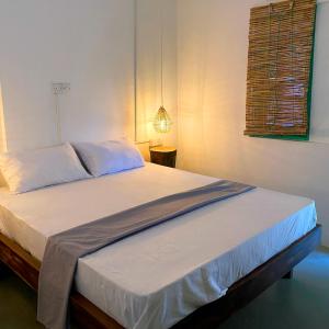 a bed in a bedroom with a lamp on a table at Fins Arugambay in Arugam Bay