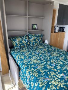 een bed met een blauw dekbed in een kamer bij beau studio au bord de la mer in Blonville-sur-Mer