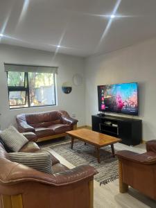 a living room with leather furniture and a flat screen tv at 2 Bedroom Apartment in Waverley, Bloemfontein in Bloemfontein