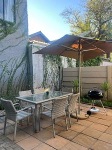 a table and chairs with an umbrella and a grill at 2 Bedroom Apartment in Waverley, Bloemfontein in Bloemfontein
