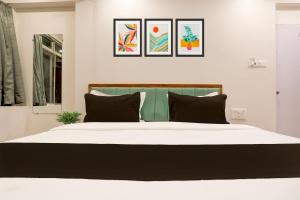 um quarto com uma grande cama branca com almofadas pretas em OYO HOTEL R CK INN em Rajkot